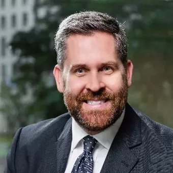 Person in a suit and tie smiling at the camera.