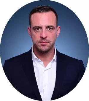 Portrait of a person in a suit against a blue background.