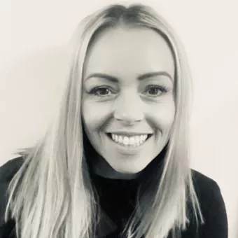 Black and white photo of a person smiling at the camera.